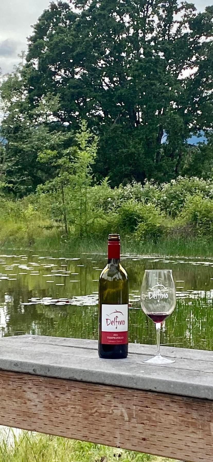 Delfino pond with Delfino wine bottle and glass on nearby bench